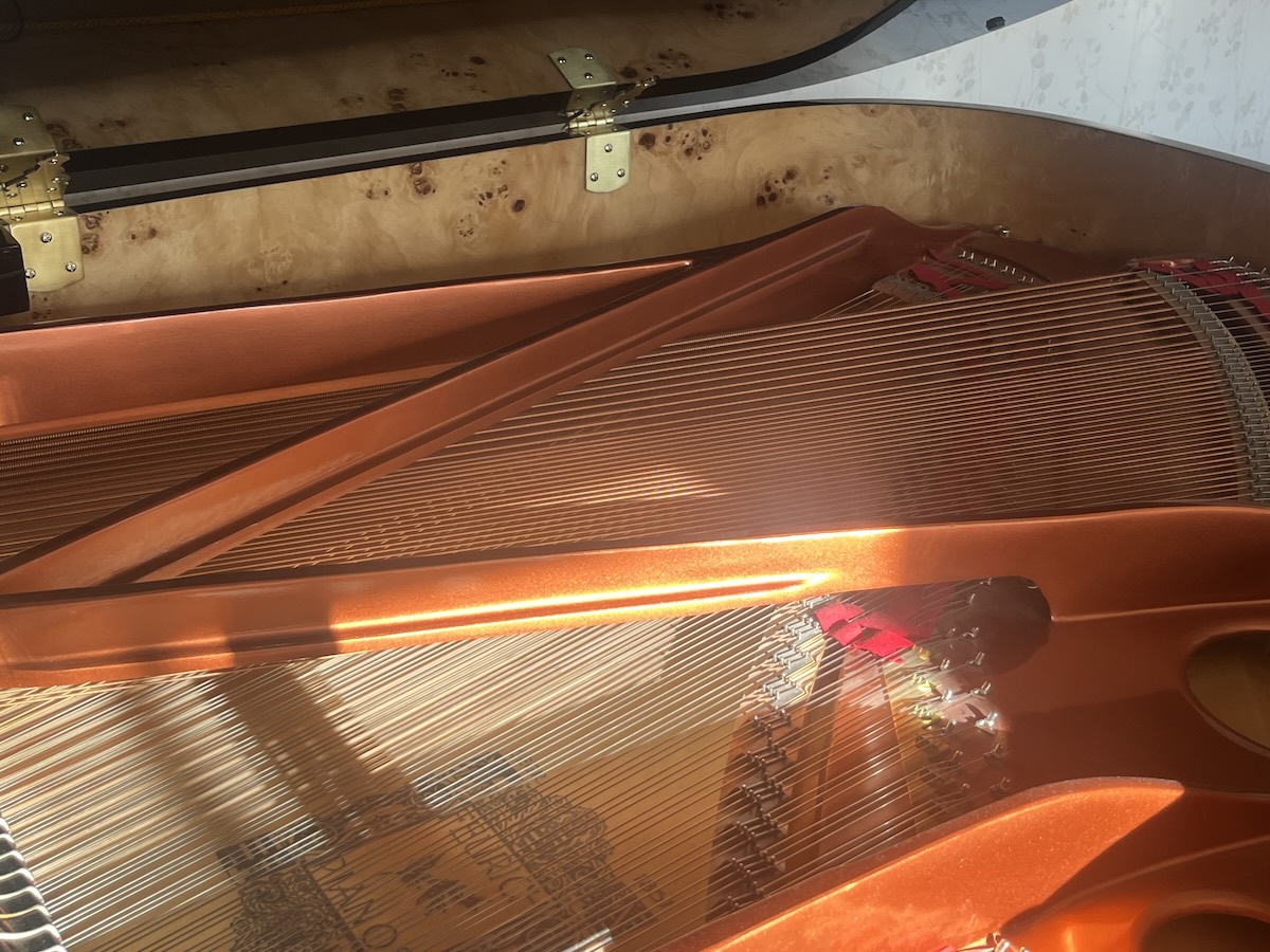 Inside of a grand piano with tuning equipment